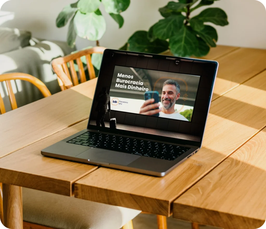 Laptop em mesa mostrando tela com "Menos Burocracia Mais Dinheiro
